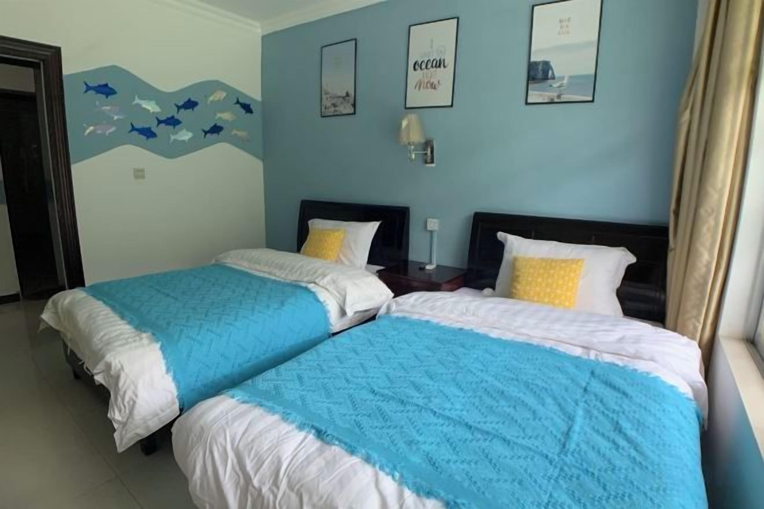 A hotel room with two beds, a wall mural, and a window with curtains.