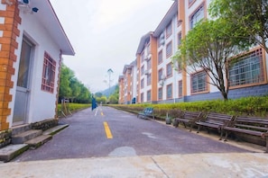 A residential street with a paved road, benches, and buildings with multiple windows and balconies.