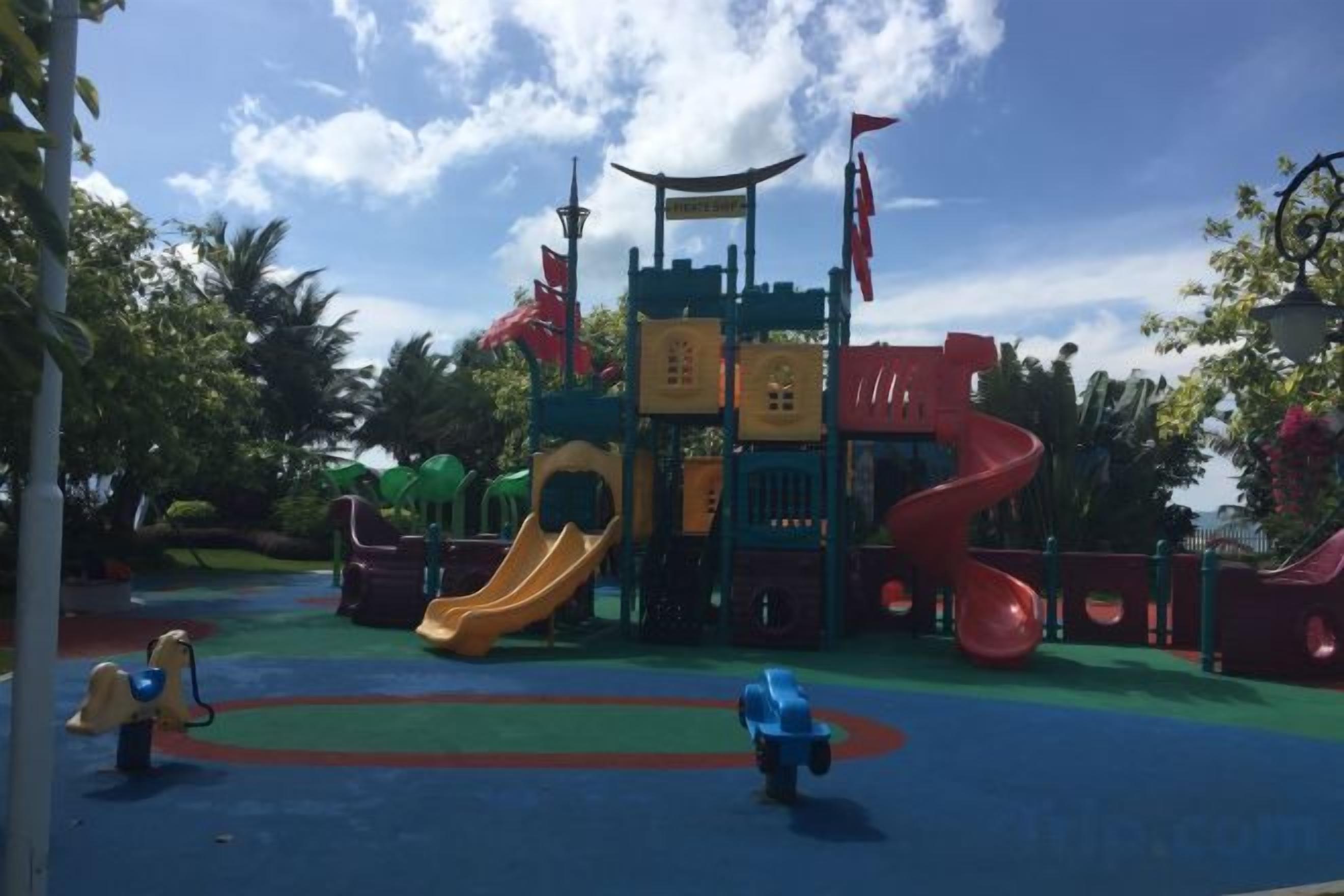 Une aire de jeux avec un toboggan, des structures d’escalade et un toboggan en spirale rouge.