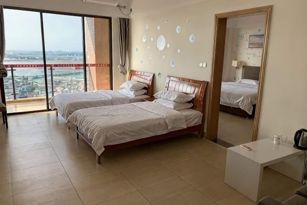 Une chambre d’hôtel avec deux lits, un bureau, une grande fenêtre donnant sur la ville et un balcon.