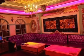 A room with a purple upholstered sofa, a flat-screen TV, and a chandelier. - Huayi Hotel (Harbin CapitaLand Airport Bus Station) (Harbin)