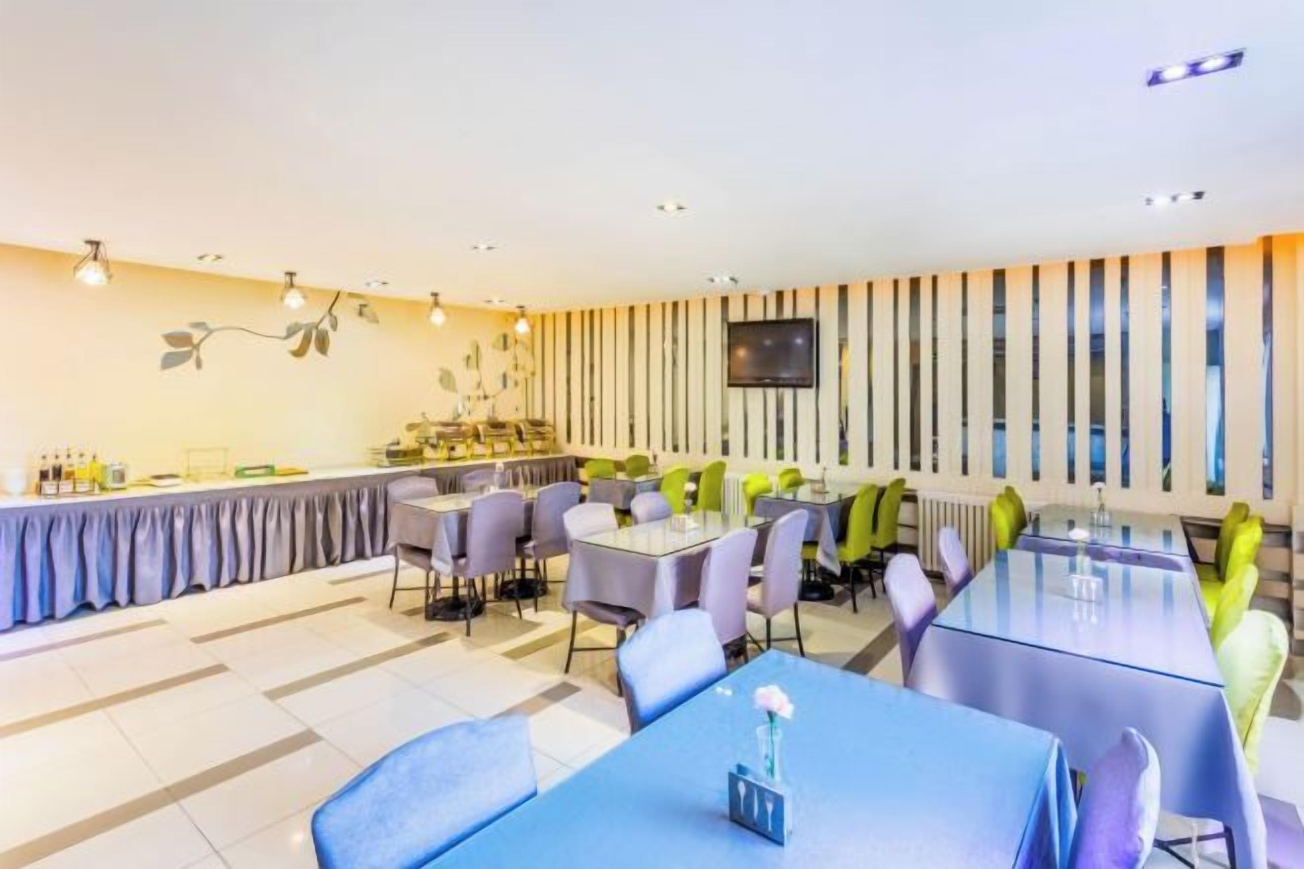 A modern dining area with tables and chairs, a bar, and a television on the wall.