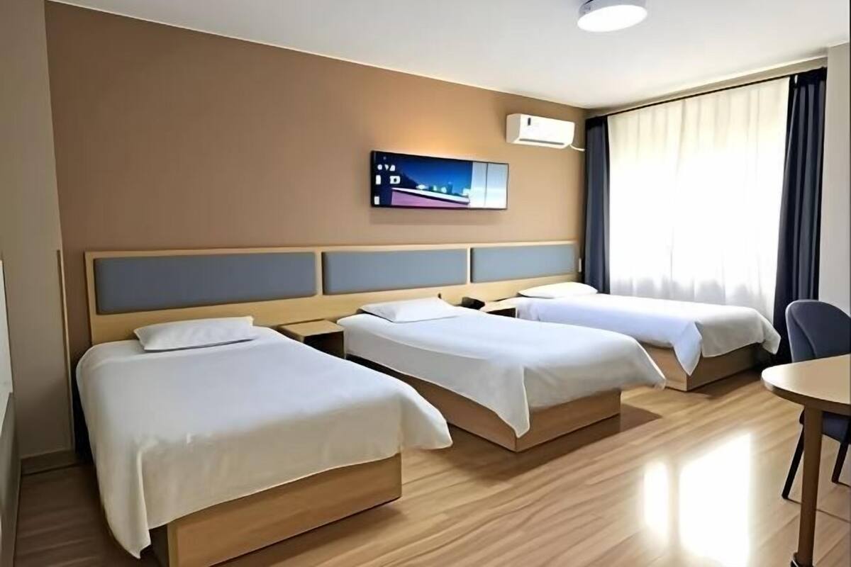 Una habitación de hotel con tres camas individuales, un escritorio y una silla.