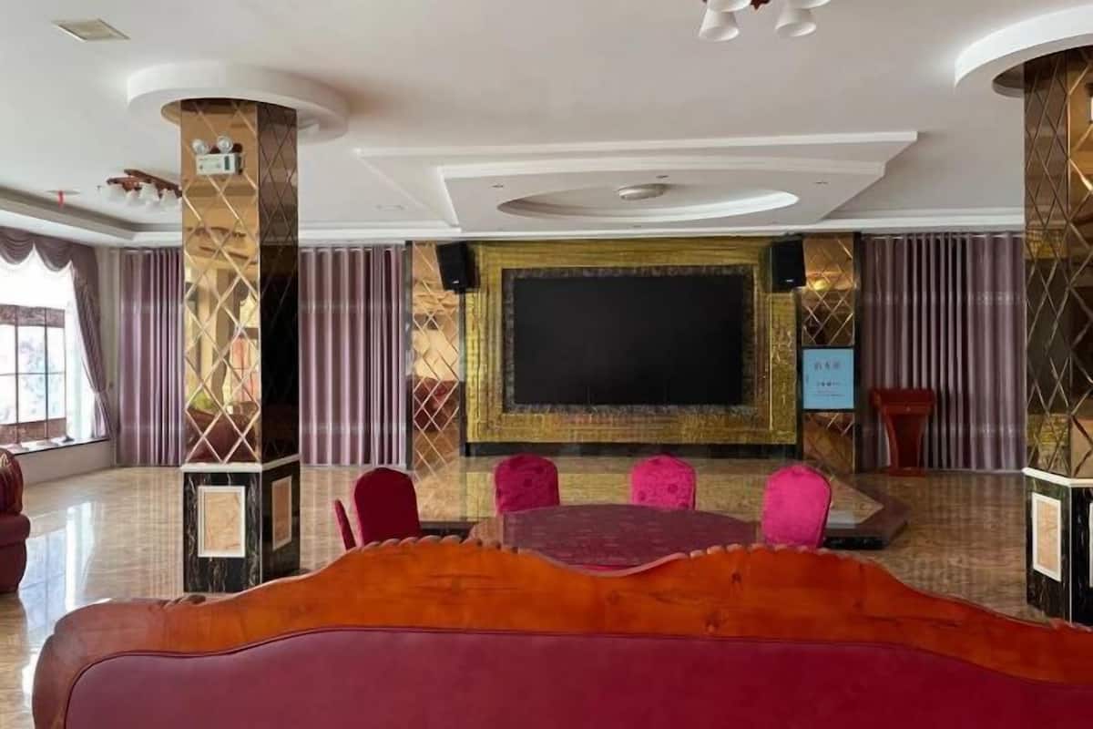 Une salle de conférence équipée d’un grand écran, d’une table ronde et de chaises rouges.