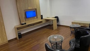 A modern living room with a flat-screen TV, wooden furniture, a glass coffee table, and black chairs. - Andes Hotel Pingjiang (Pingjiang)
