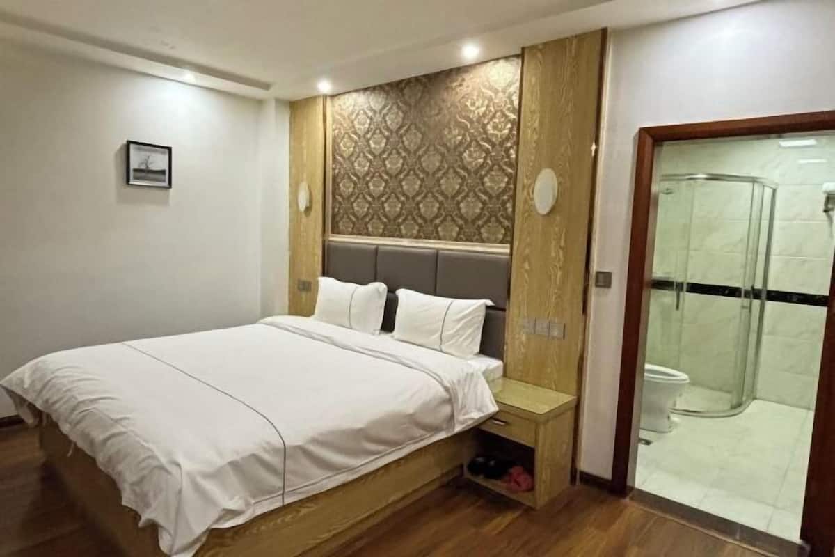 Une chambre à coucher comprenant un lit, une table de chevet et un espace douche.
