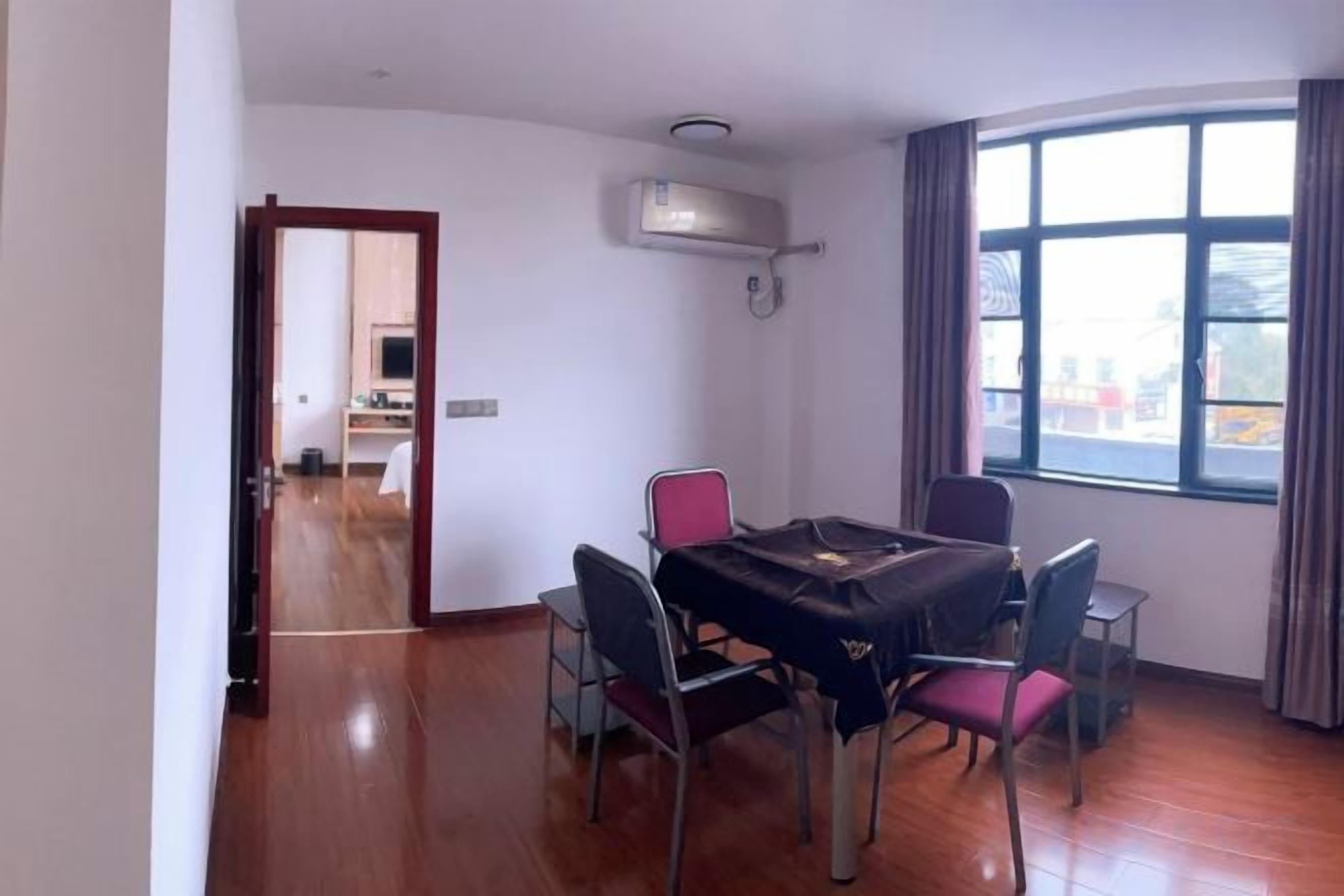 A dining area with a table and chairs, a window with curtains, and an air conditioning unit.