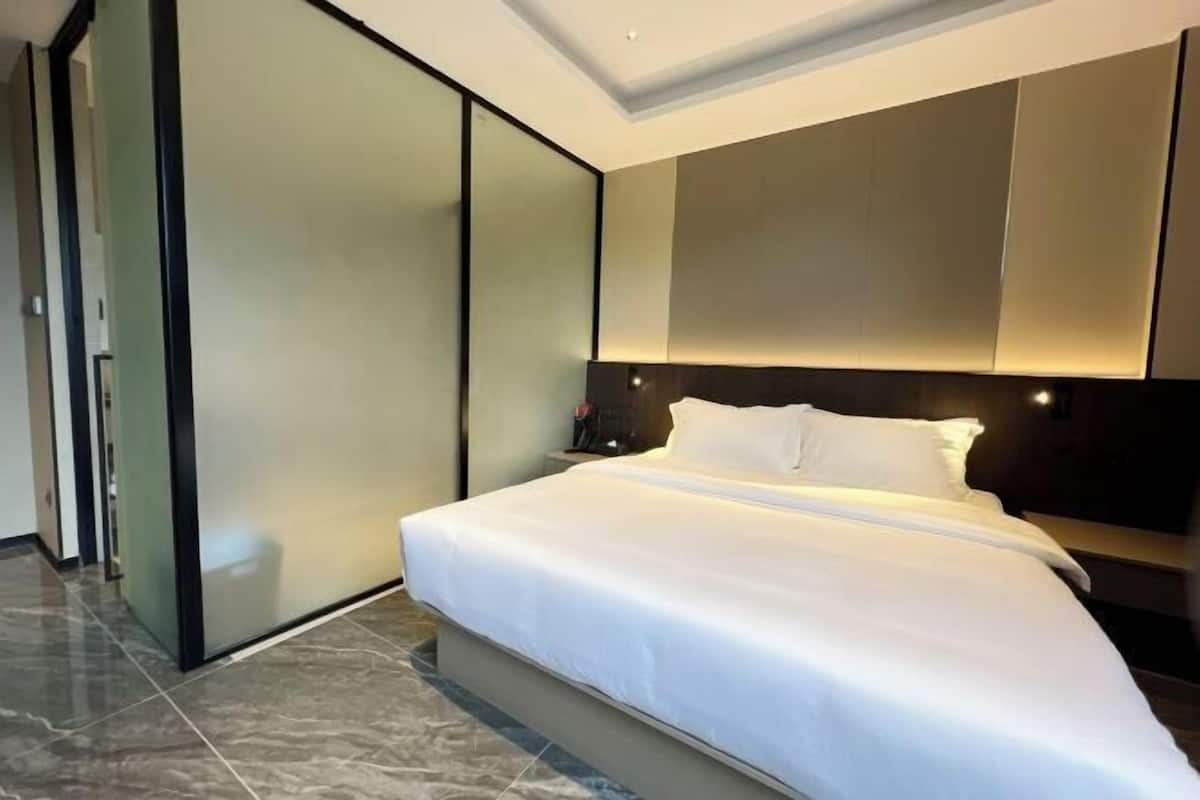 Una habitación de hotel moderna con una cama grande, un armario de puertas correderas y un cabecero oscuro.