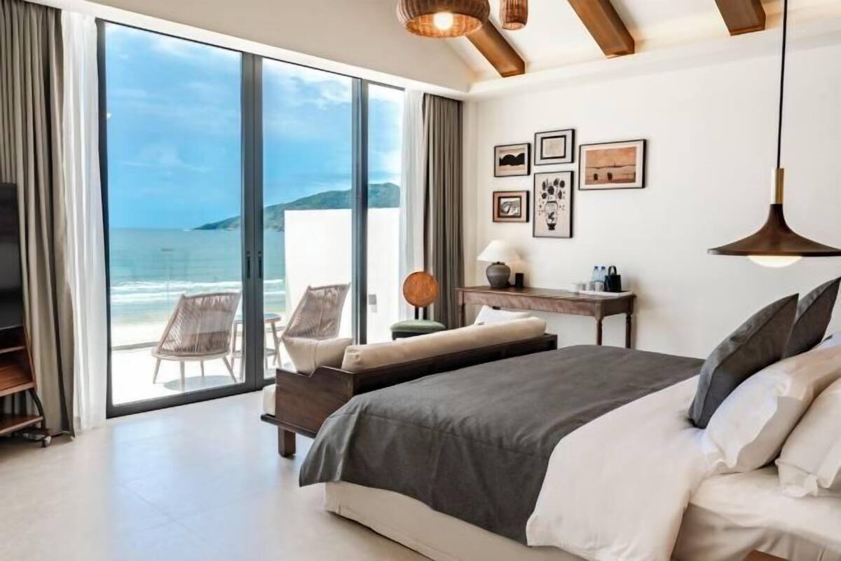 Un dormitorio con una cama grande, un escritorio, una silla y vista al mar.