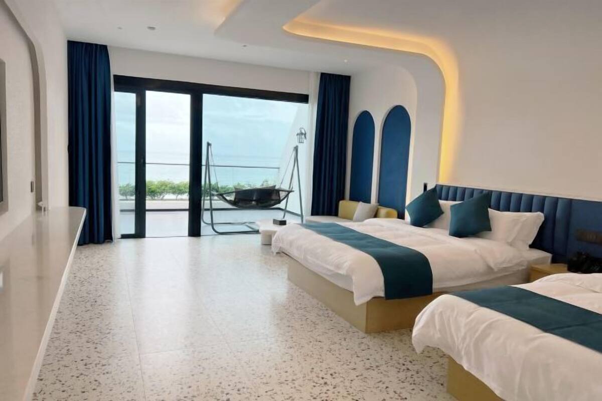 Una habitación de hotel moderna con dos camas, un balcón y una silla colgante.