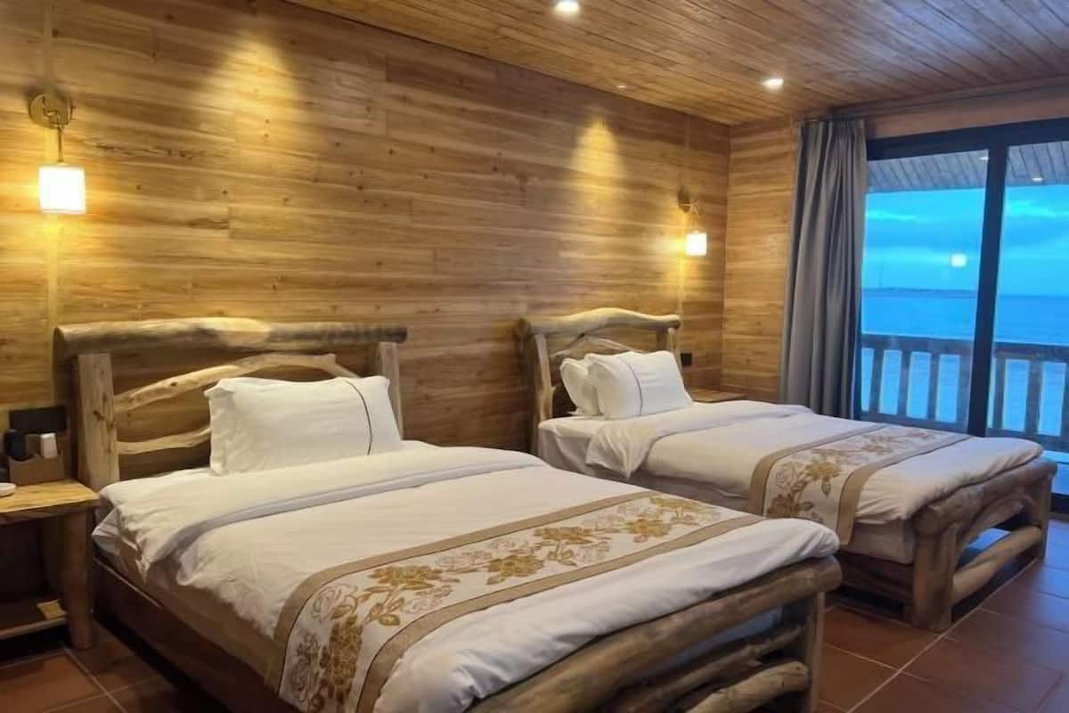 Una habitación tipo cabaña de madera con dos camas, cabeceras de madera y un ventanal con vistas.