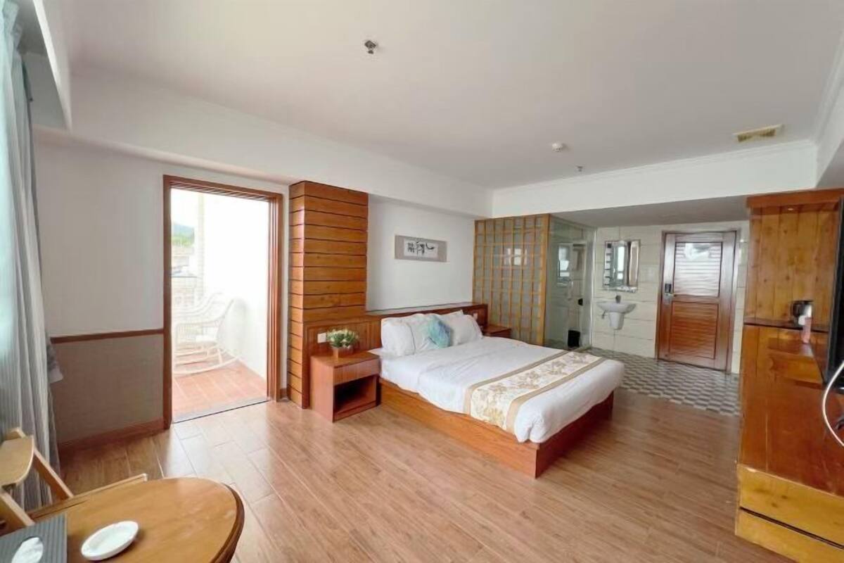 Un dormitorio con una cama de madera, una mesita de noche, una silla y vistas al exterior.