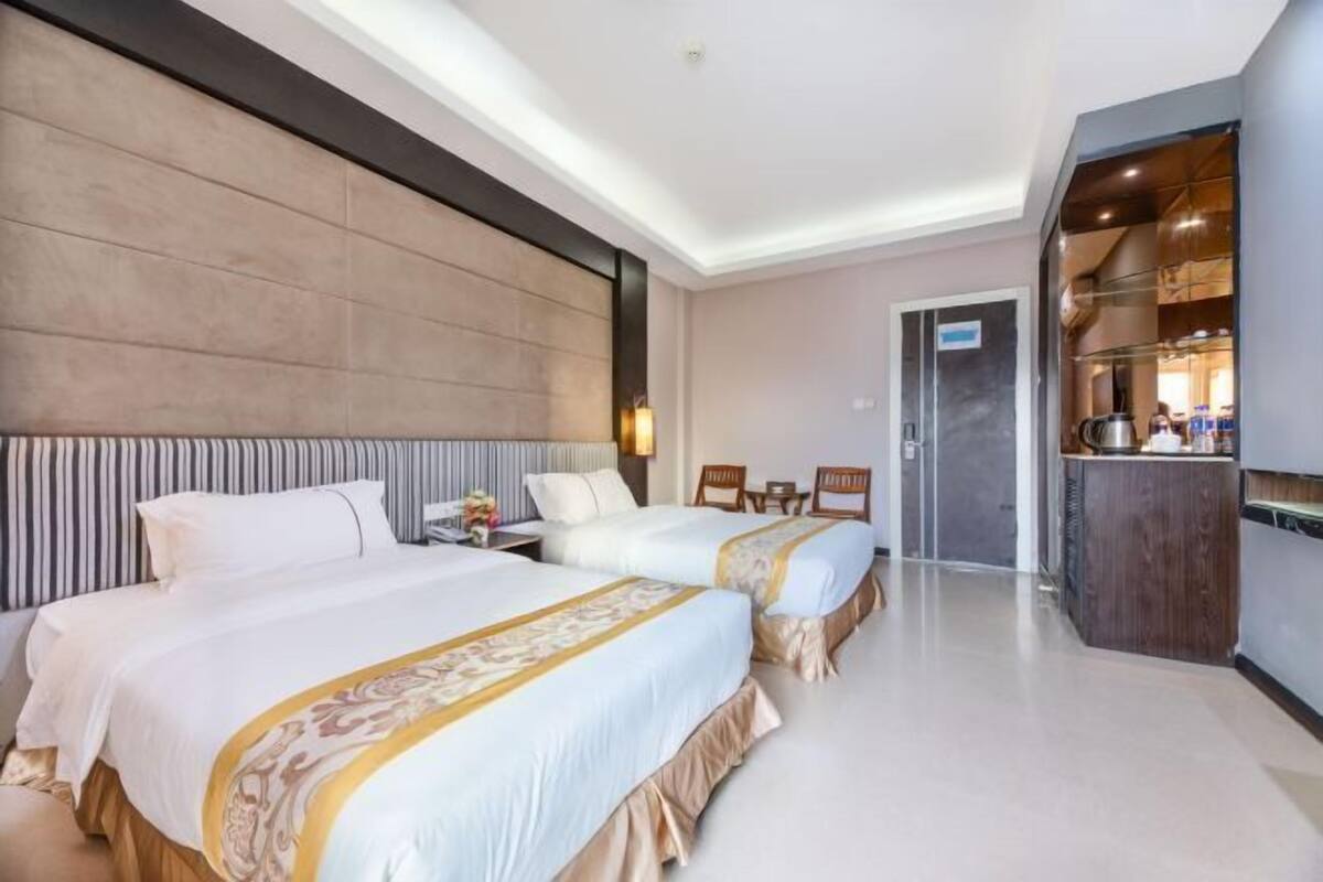 Una habitación de hotel con dos camas, minibar, escritorio y baño.