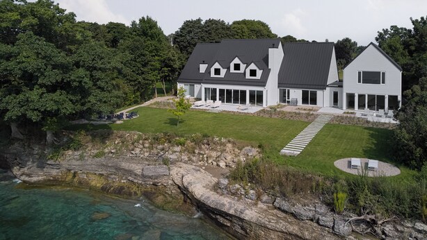 A modern two-story house with a large deck and a view of the ocean.