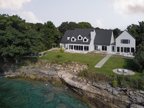 Una casa moderna de dos pisos con una amplia terraza y vista al océano.