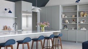 A modern kitchen with a central island, bar stools, and a decorative vase.
