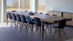 A modern dining area with a long table, black chairs, and a large pendant light.