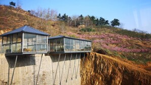 A glass-roofed building on a hillside with a view of purple flowers and trees. - Monkey Mountain Villa Hotel (Mengyin)