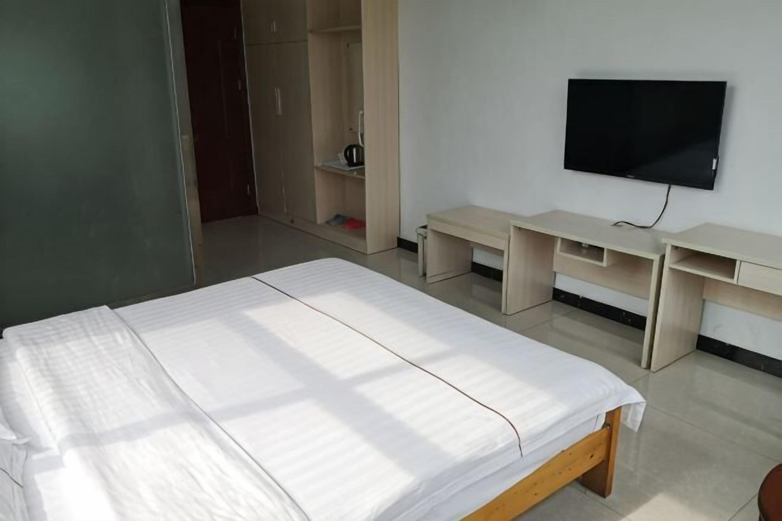 Quarto com uma cama, televisão e escrivaninha.
