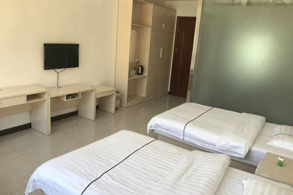Una habitación de hotel con dos camas, un escritorio, un televisor y un armario.