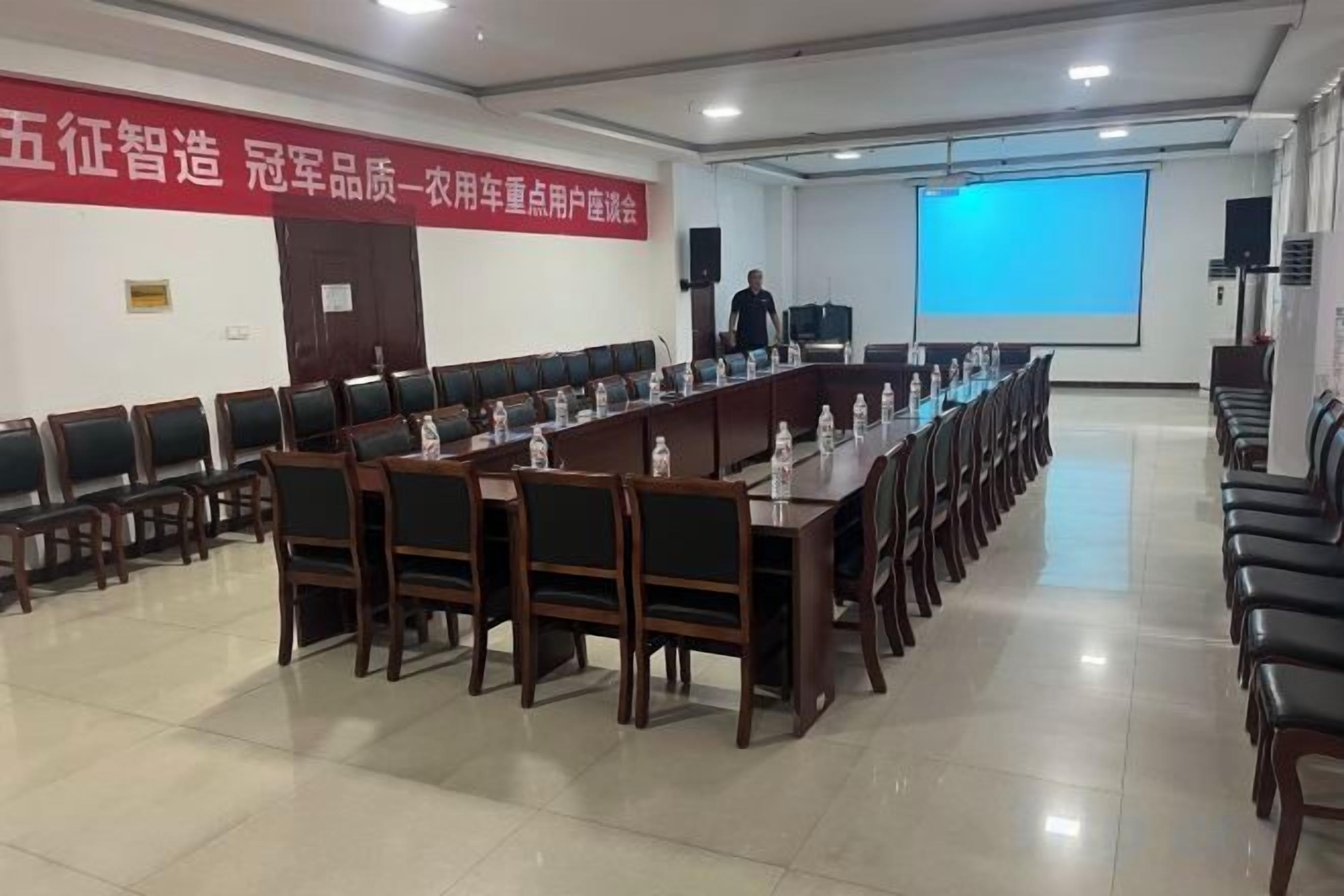 Une salle de conférence avec une longue table, des chaises, un écran de projection et une banderole accrochée au mur.
