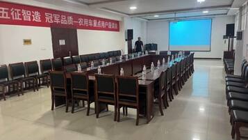 Une salle de conférence avec une longue table, des chaises, un écran de projection et une banderole accrochée au mur.