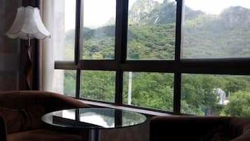 Una habitación con un ventanal grande, una mesa redonda de cristal y dos sillones marrones.