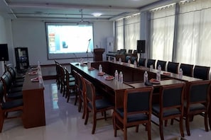 A conference room with a long table, chairs, a projector screen, and a large window with curtains. - Monkey Mountain Villa Hotel (Mengyin)