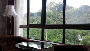 A room with a large window, a round table, and two chairs. - Monkey Mountain Villa Hotel (Mengyin)
