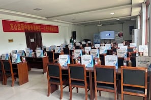 A conference room with tables and chairs, a red banner, and informational posters.