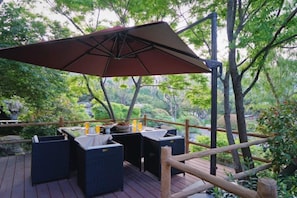 An outdoor deck with a table and chairs, surrounded by greenery. - Yanzi Resort (Jinan)