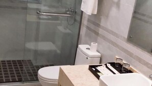 Un baño moderno con cabina de ducha de vidrio, inodoro y lavamanos con encimera.