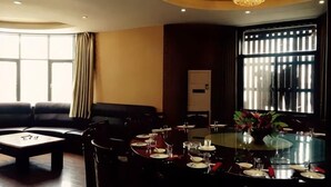 Un comedor con una mesa redonda dispuesta para cuatro personas, un sofá y una araña.