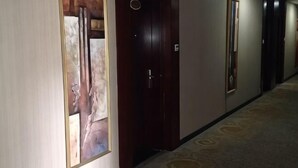Un pasillo con puertas, piso alfombrado y un cuadro en la pared.