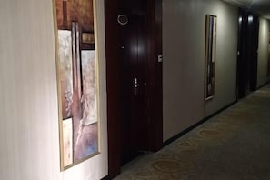 A hallway with doors, a carpeted floor, and a framed picture on the wall. - Tiantian Holiday Hotel (Tongcheng)