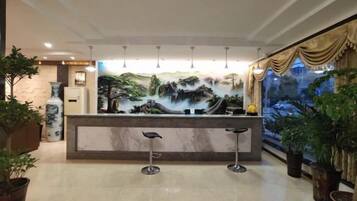 A reception area with a marble counter, two bar stools, and a large mural depicting a landscape.