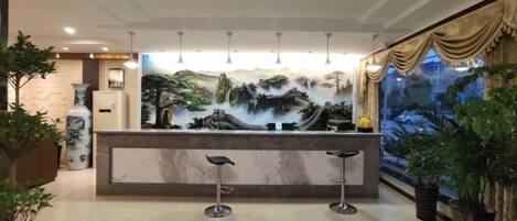 A reception area with a marble counter, two bar stools, and a large mural depicting a landscape.
