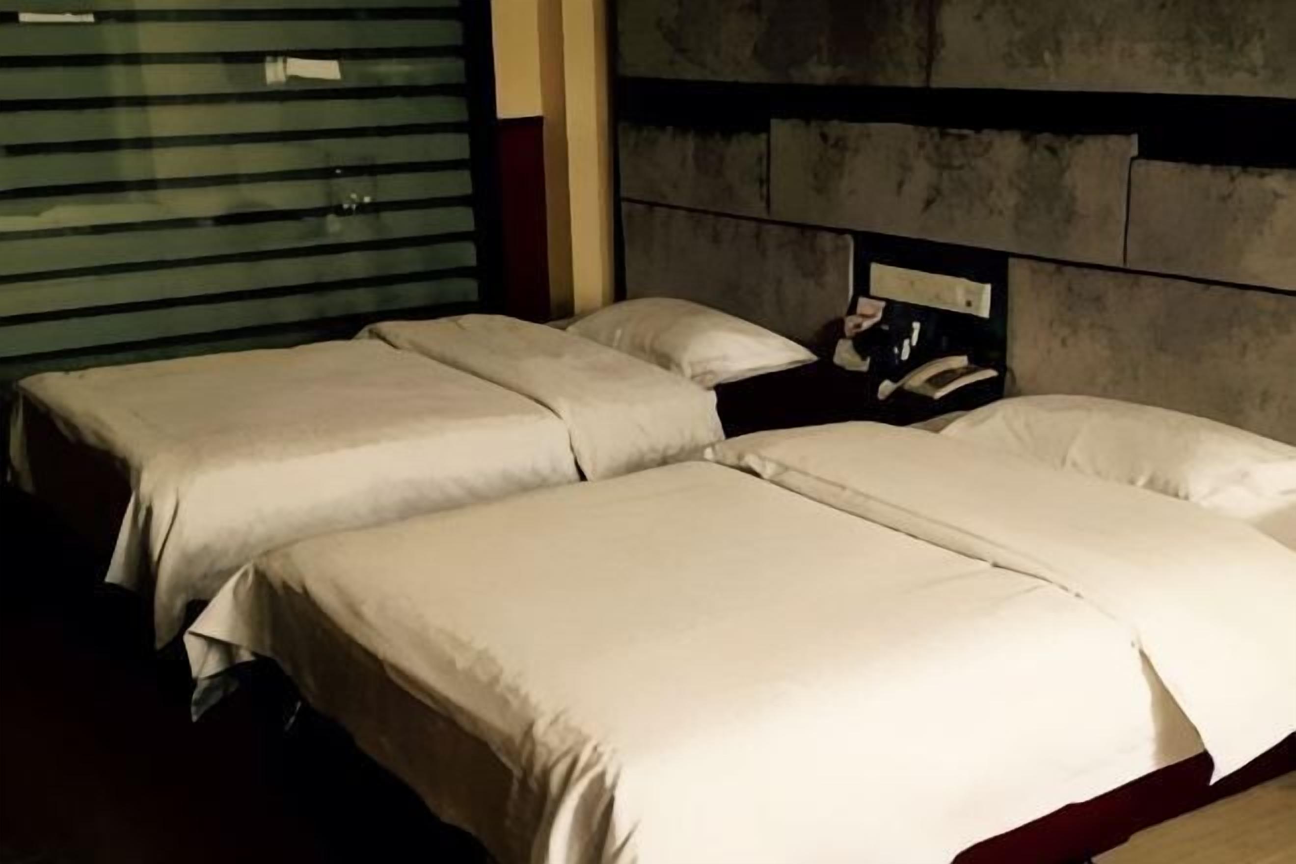 Una habitación de hotel con dos camas, cabecera y teléfono.