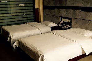 Una habitación de hotel con dos camas, cabecera y teléfono.