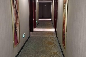A hallway with patterned carpet, doors on either side, and a light at the end. - Tiantian Holiday Hotel (Tongcheng)