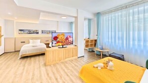 Een hotelkamer met een bed, een televisie, een bureau met een laptop en een raam met gordijnen.