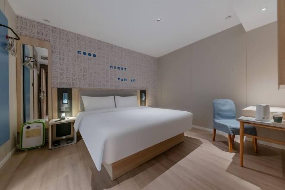 A modern hotel room with a large bed, bedside tables, a desk, and a chair.
