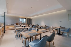 Un comedor moderno con mesas y sillas, una barra con exhibición, y un amplio ventanal.