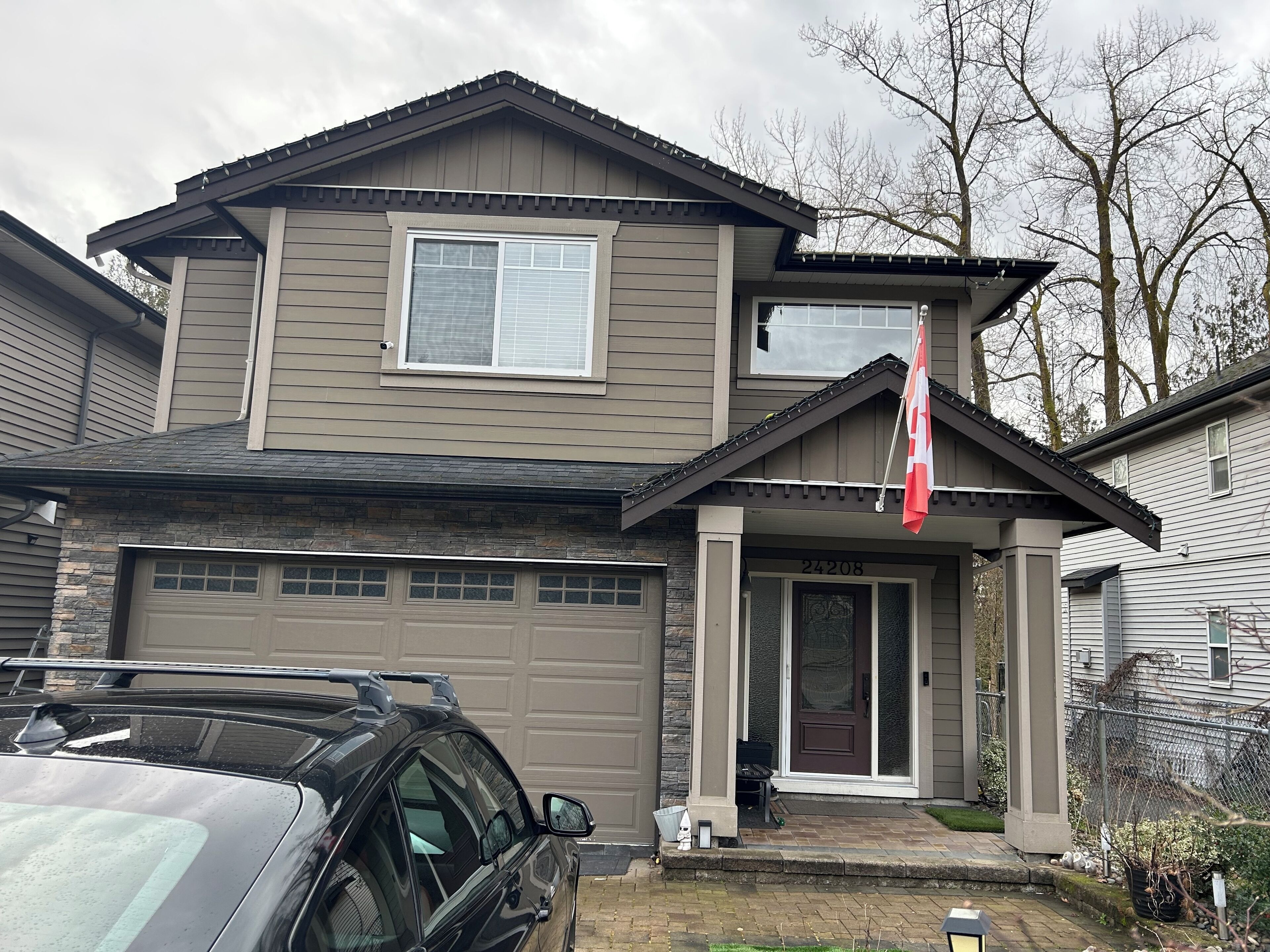 Une maison à deux étages avec un garage, un drapeau et une façade en pierre.