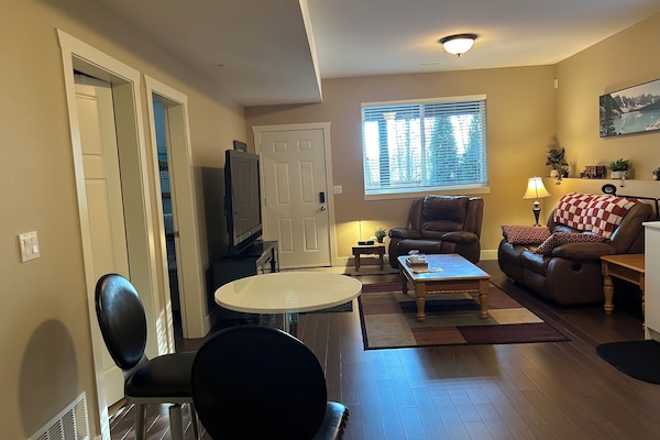 Opened living area with 9ft ceiling, reclining chair and love seat.