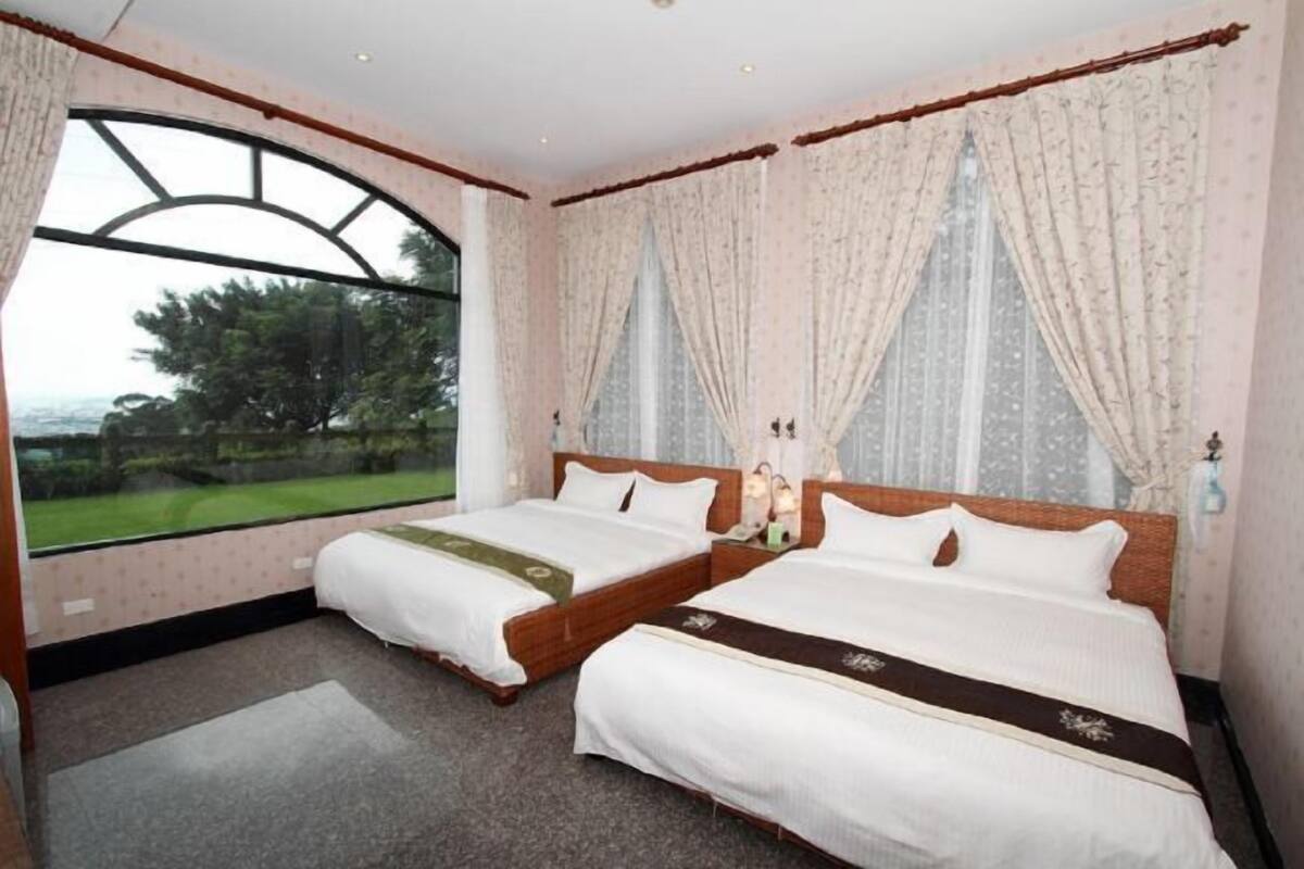Een hotelkamer met twee bedden, grote ramen en gordijnen.