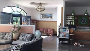A hotel lobby with a sofa set, a fan, a coffee bar, and a dog lying on the floor.