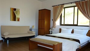 A bedroom with a bed, a wooden bench, a wardrobe, and a window with curtains.