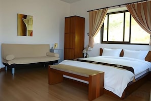 A bedroom with a bed, a bench, a sofa, a wardrobe, and a window with curtains. - Cloud Top Landscape Hotel (Hualien)