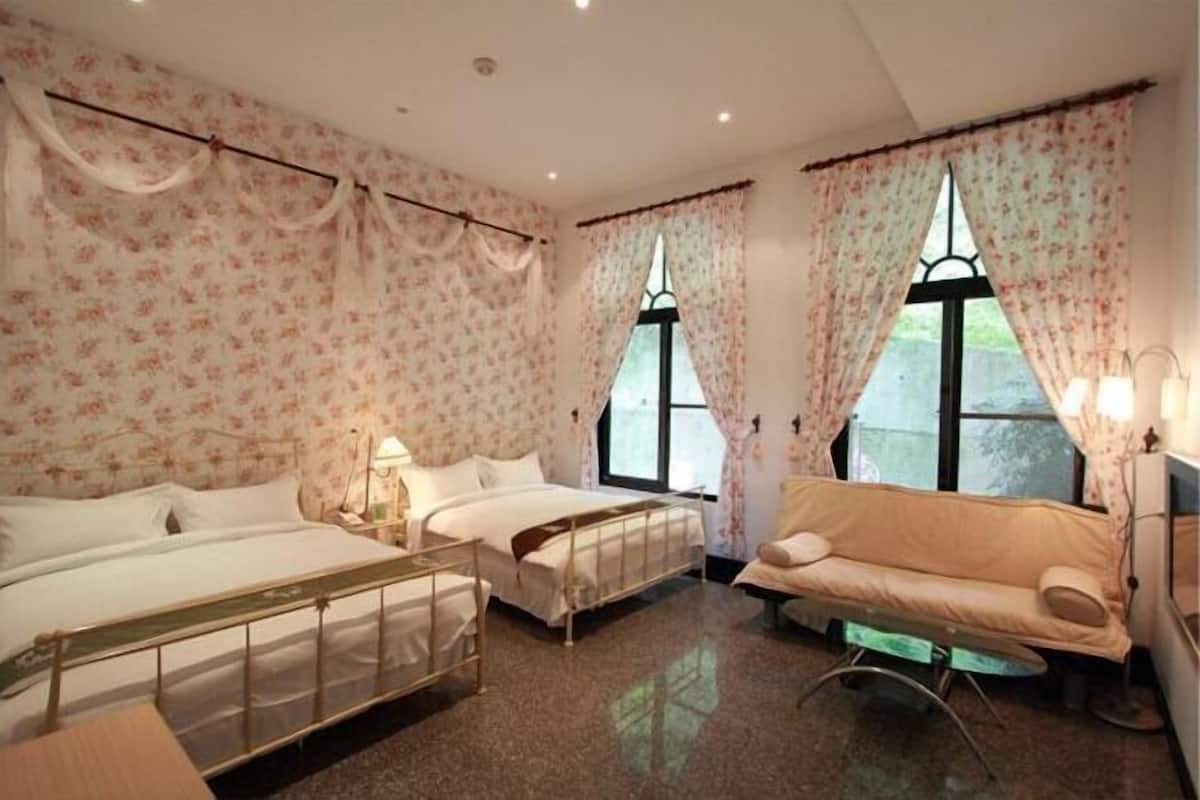 Een slaapkamer met twee bedden, een bank, een nachtkastje en een raam met gordijnen.